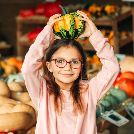 Adorable girl selecting her fall pumpkins at a local farm market.
